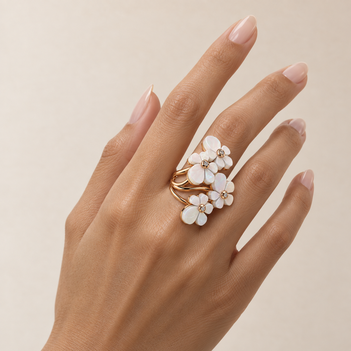 Gisela Mother of Pearl Tetra Ring in 18K gold with four mother-of-pearl flowers, worn on a hand with natural almond nails
